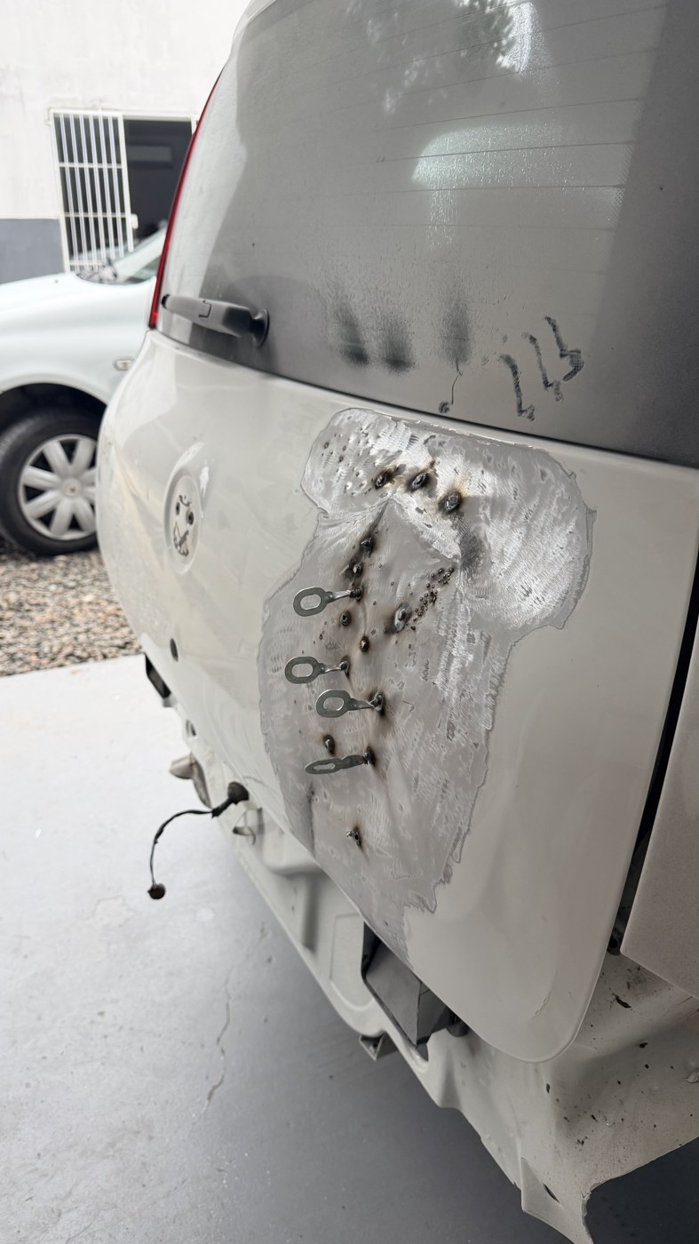 Reparo em andamento na traseira do Fiat Uno com repuxo e preparação