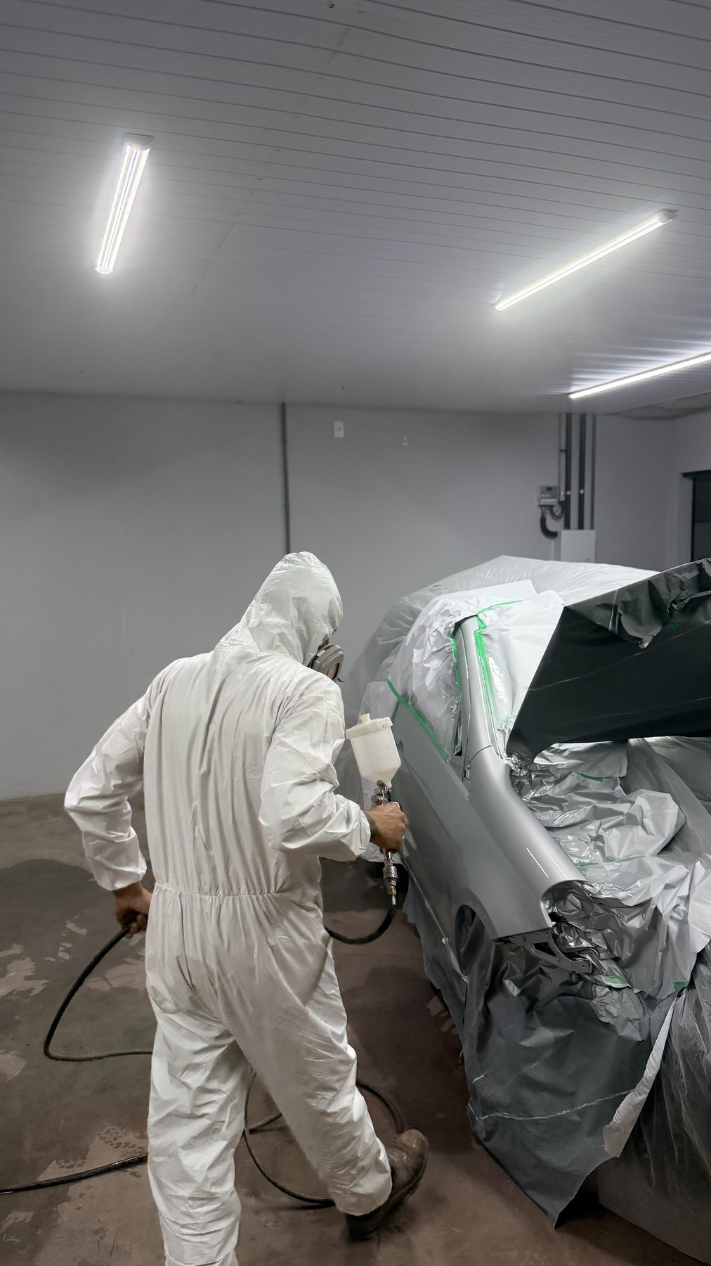 Profissional da FastBlu realizando a pintura do veículo na cabine